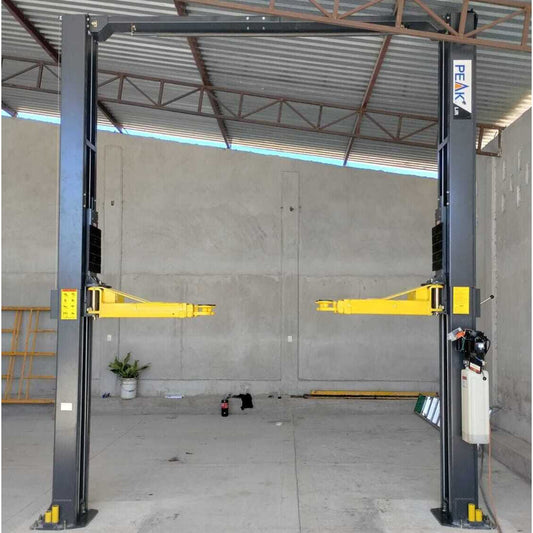 Elevador de 2 columnas Peak 212C instalado en taller automotriz, modelo clear-floor con brazos telescópicos y desbloqueo de seguridad de un solo punto, robusto y seguro para autos, SUVs y camionetas.