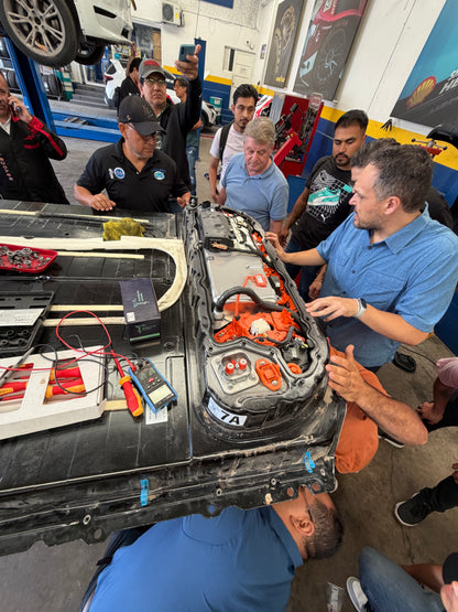 Capacitación práctica en baterías EV con diagnóstico y reparación de alta tensión, instructor explicando módulos y conexiones de batería en vehículo eléctrico