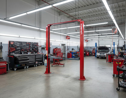 Elevador hidráulico Launch TLT245AT instalado en taller automotriz, diseño asimétrico con bloqueo automático y travesaño superior para servicio general.